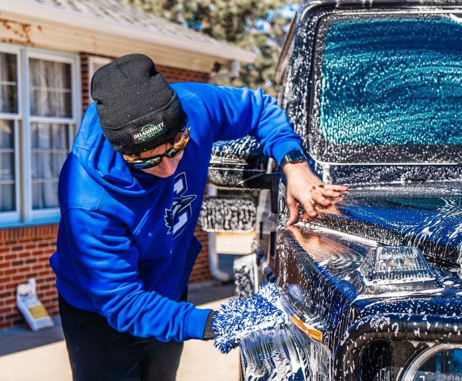 Cole hand-washing a black truck with a wash mitt