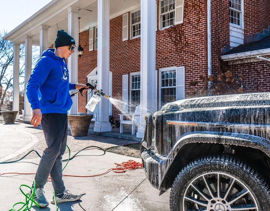 Cole applying foam to a black SUV with a foam cannon