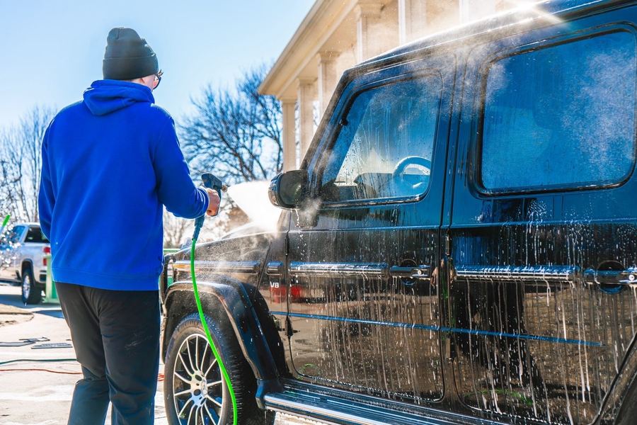 Cole rinsing a black G-Wagon with a pressure washer