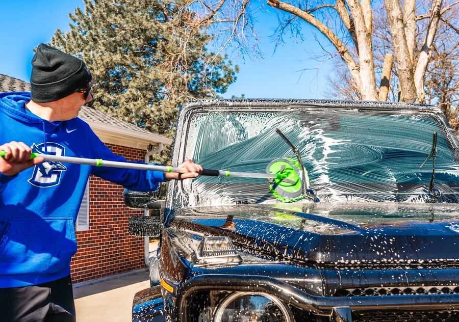 Cole cleaning a windshield with an extension brush