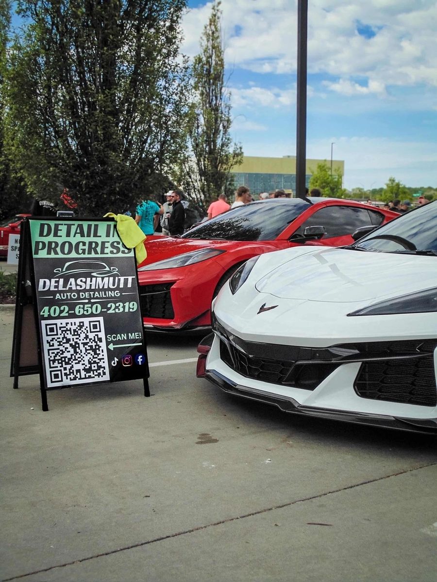 DeLashmutt Auto Detailing signage displayed between two Corvettes at a local car show