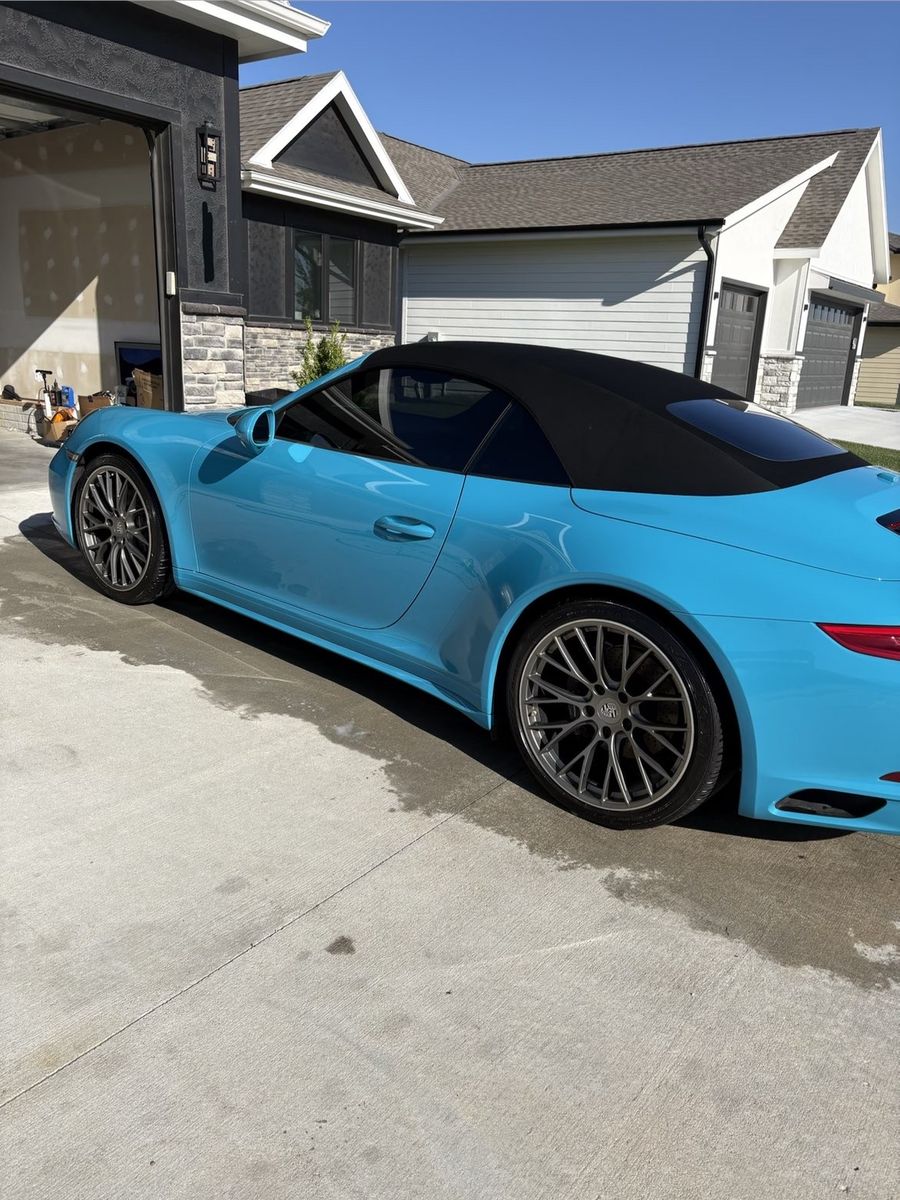 Glossy Miami-blue Porsche 911 Carrera, front 3/4 angle in driveway